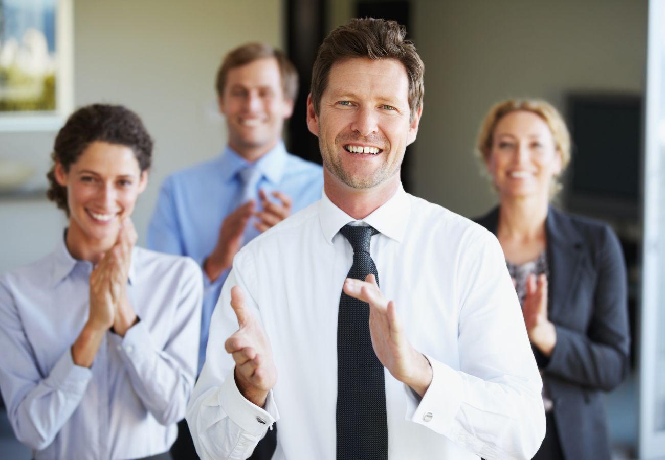 Group of people in business attire clapping and smiling