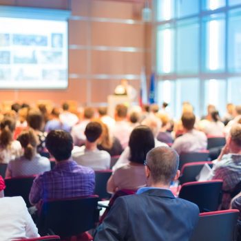 Rear view of a conference room filled with people viewing a presentation